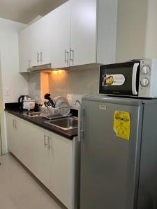 een keuken met een koelkast, een wastafel en een magnetron bij Our Home at JAZZ Residences -Cable, Wifi & Netflix in Manilla