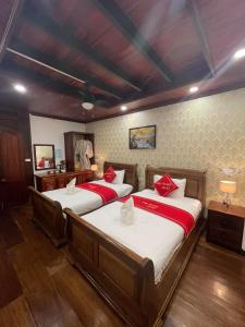 a bedroom with two beds with red pillows at Luang Prabang Villa Sirikili River View in Luang Prabang