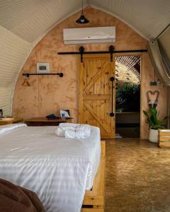 ein Schlafzimmer mit einem weißen Bett und einer Holztür in der Unterkunft La Levée Resort in Sai Yok