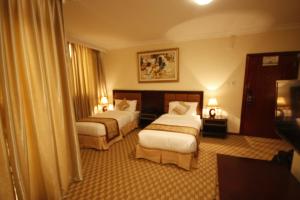 a hotel room with two beds and two lamps at caravan Hotel Addis in Addis Ababa