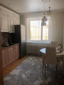 a kitchen with a table and a refrigerator and a window at at HOME in Prigorodnyy