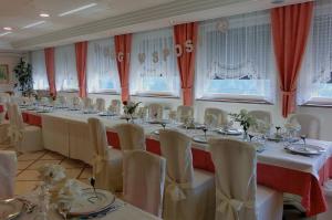 a large room with a long table with white chairs at Hotel Belvedere Wellness & Family in Baselga di Pinè