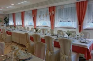 Cette grande chambre comprend une grande table avec des chaises blanches. dans l'établissement Hotel Belvedere Wellness & Family, à Baselga di Pinè