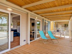 una veranda con sedie blu e un tavolo sopra di Mobile Home Omisalj with Seaview at Beach a Omišalj (Castelmuschio)
