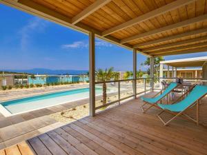 a deck with a table and chairs next to a swimming pool at Mobile Homes in Camping Omisalj, island Krk, with swimmingpool in Omišalj