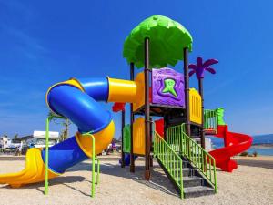 a playground with a slide in the sand at Mobile Homes in Camping Omisalj, island Krk, with swimmingpool in Omišalj