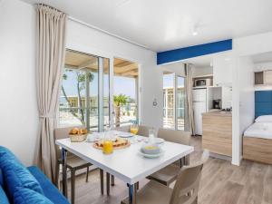 una sala da pranzo e un soggiorno con tavolo e sedie bianchi di Mobile Home Omisalj with Seaview at Beach a Omišalj (Castelmuschio)