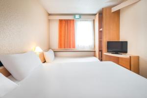 um quarto de hotel com duas camas e uma televisão em ibis Niort Marais Poitevin em Niort