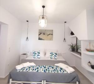 a white bedroom with two beds and a chandelier at Kiki's Apartments in Barbati