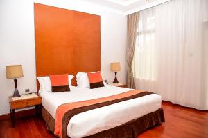 a hotel room with a large bed with orange pillows at Alba Hotel Meru in Meru