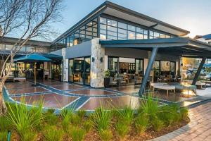 a large building with a patio with tables and umbrellas at Modern 3-bed Garden Apartment in Waterfall in Midrand