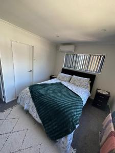1 dormitorio con 1 cama con manta verde en Auckand Holiday in the Golden Circle, en Auckland