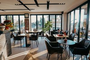 ein Restaurant mit Tischen und Stühlen und Fenstern in der Unterkunft Nord Hotel Boutique in Shkodra