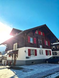 インターラーケンにあるAdventure Guesthouse Interlakenの赤いシャッター付きの大きな木造家屋