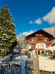 una casa de madera en la nieve con una valla en Adventure Guesthouse Interlaken, en Interlaken