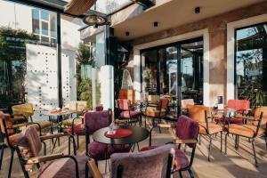 ein Restaurant mit bunten Stühlen, Tischen und Fenstern in der Unterkunft Nord Hotel Boutique in Shkodra