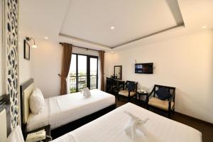 a hotel room with two beds and a balcony at Hoi An Rose Garden Hotel in Hoi An