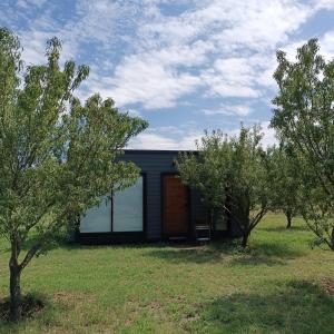 ein schwarzes Haus mit Bäumen davor in der Unterkunft La Canaria Casa de Campo in Colonia Caroya