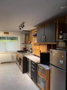 una cocina con armarios de madera y electrodomésticos de acero inoxidable en Le clos marin, en Blendecques