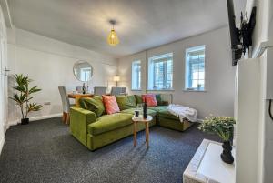 a living room with a green couch and a table at Brewery Loft - 3 Bedroom Bright Spacious apartment in the centre of town, Wifi, Netflix in Cirencester