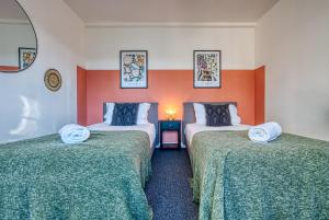 two beds in a room with orange and white walls at Brewery Loft - 3 Bedroom Bright Spacious apartment in the centre of town, Wifi, Netflix in Cirencester