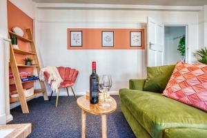 a living room with a green couch and a bottle of wine at Brewery Loft - 3 Bedroom Bright Spacious apartment in the centre of town, Wifi, Netflix in Cirencester