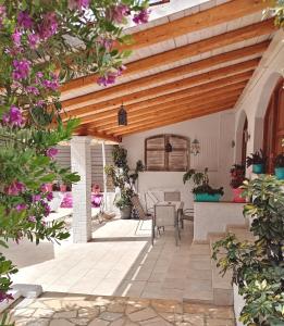 an outdoor patio with a wooden ceiling and flowers at Kiki's Apartments in Barbati