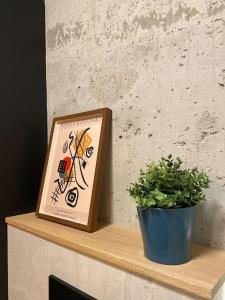 ein Bild und eine Pflanze auf einem Holzregal in der Unterkunft Art & Pleasure WAW z bezpłatnym parkingiem in Warschau