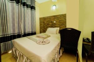 een kleine slaapkamer met een bed en een stoel bij Latitude 1 Suites in Kampala +16 foto's