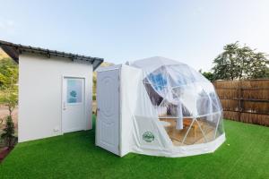 a greenhouse on a lawn next to a house at Ikigawa Home in Ban Pha Khap