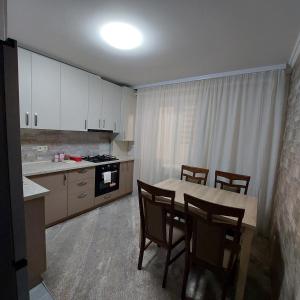 a kitchen with a table and chairs and a kitchen with white cabinets at Apartament lux new in Chişinău