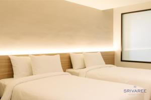 2 Betten in einem Zimmer mit einer Leinwand in der Unterkunft The Srivaree Airport Hotel in Samutprakarn