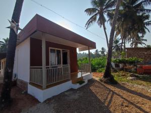 a small house with palm trees in front of it at Coral Beach Cottage in Māvalli