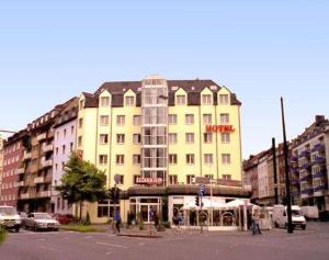 un gran edificio amarillo en una calle de la ciudad con coches en Hotel Residenz, en Düsseldorf