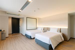 una habitación de hotel con 2 camas y una pantalla en The Srivaree Airport Hotel en Samutprakarn