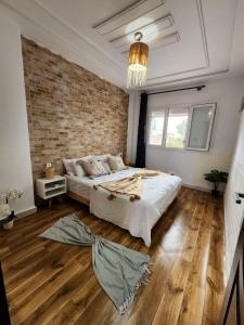 a bedroom with a large bed and a brick wall at FamilyConfort Saidia in Saïdia