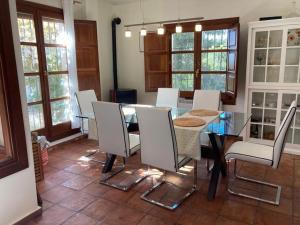 ein Esszimmer mit einem Glastisch und weißen Stühlen in der Unterkunft Alfapinoalegre in Alfacar