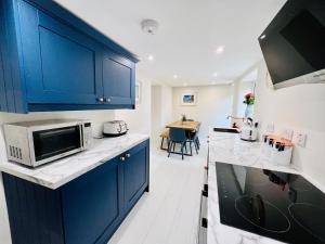 a kitchen with blue cabinets and a kitchen with a table at 20 Lisburn Street in Alnwick