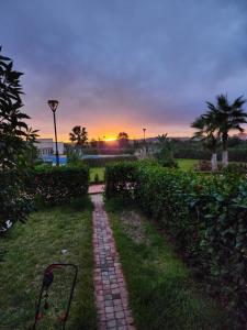 a brick path in the grass with a sunset in the background at FamilyConfort Saidia in Saïdia