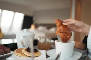 a person is holding a croissant in a cup at Seeko'o Hotel Bordeaux in Bordeaux