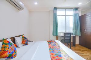 Schlafzimmer mit einem Bett, einem Schreibtisch und einem Fenster in der Unterkunft FabHotel Hexa Ghaziabad in Ghaziabad