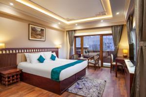 レーにあるAshoka Ladakhのベッド、デスク、バルコニーが備わるホテルルームです。