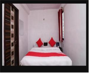 a bedroom with a large white bed with red pillows at Ganga Guest House By WB Inn in Agra