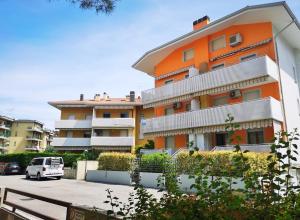 an orange and white building in a parking lot at Appartamenti Elena in Grado