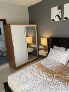 a bedroom with a bed with two lamps and two mirrors at Aminah’s Space - Jobz Luxury Rental in Bijilo