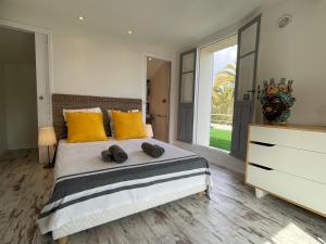 une chambre avec un grand lit avec des oreillers jaunes dans l'établissement Villa de charme vue mer et piscine chauffée sur les hauteurs de Golf Juan, à Vallauris