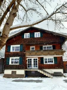 un bâtiment en briques avec des fenêtres blanches et un arbre dans l'établissement Ferienhaus Schindeler, à Mellau