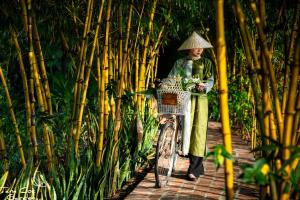 una donna in piedi accanto a una bicicletta con un cesto di Tam Coc Garden Resort a Ninh Binh