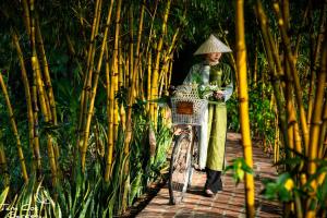 a woman standing next to a bike with a basket at Tam Coc Garden Resort in Ninh Binh