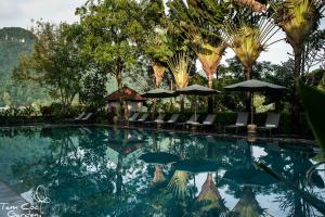 una piscina en un complejo con sillas y sombrillas en Tam Coc Garden Resort en Ninh Binh